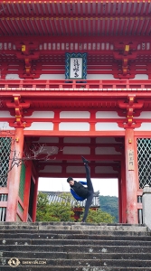 Tancerz Teo Yin wyciąga stopę w stronę sufitu frontowej bramy Kiyomizu-dera (Niomon 仁王門). Teo m&oacute;wi, że to jest jego ulubiona figura, ponieważ aby ją zrobić potrzebuje tylko odrobinę rozgrzewki... (Ben Chen)